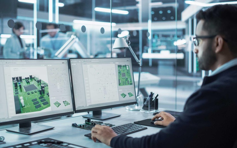 Industrial Engineer Developing 3D Model of a Circuit Motherboard on Computer CAD Software in a Factory