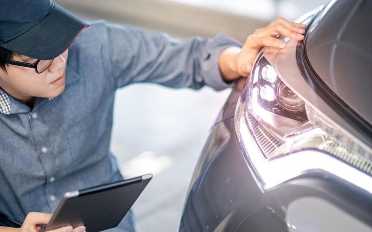 young mechanical maintenance engineer working in automotive industry checking headlight