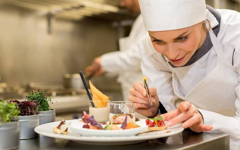 Chef adding garnish while inspecting food