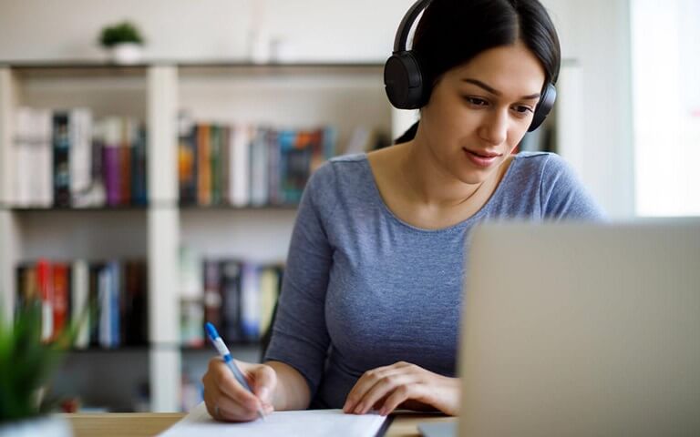 Une femme portant un casque d’écoute qui regarde un écran