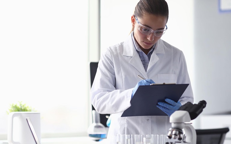 Femme en blouse blanche de laboratoire étudiant des dossiers médicaux