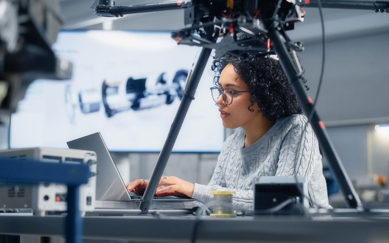 Concentrated female engineer developing software for drone control in the research center laboratory