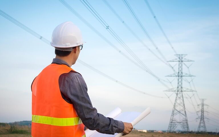 Un travailleur à l'extérieur, regardant des lignes électriques