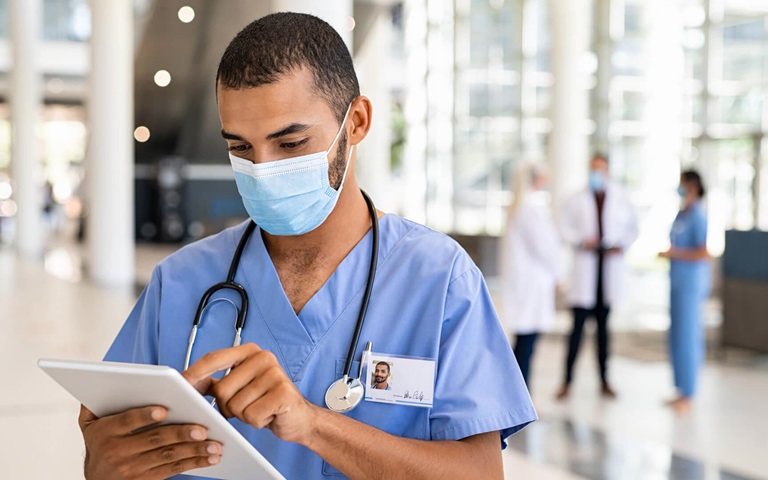 healthcare working wearing ppe reviewing patient data on tablet