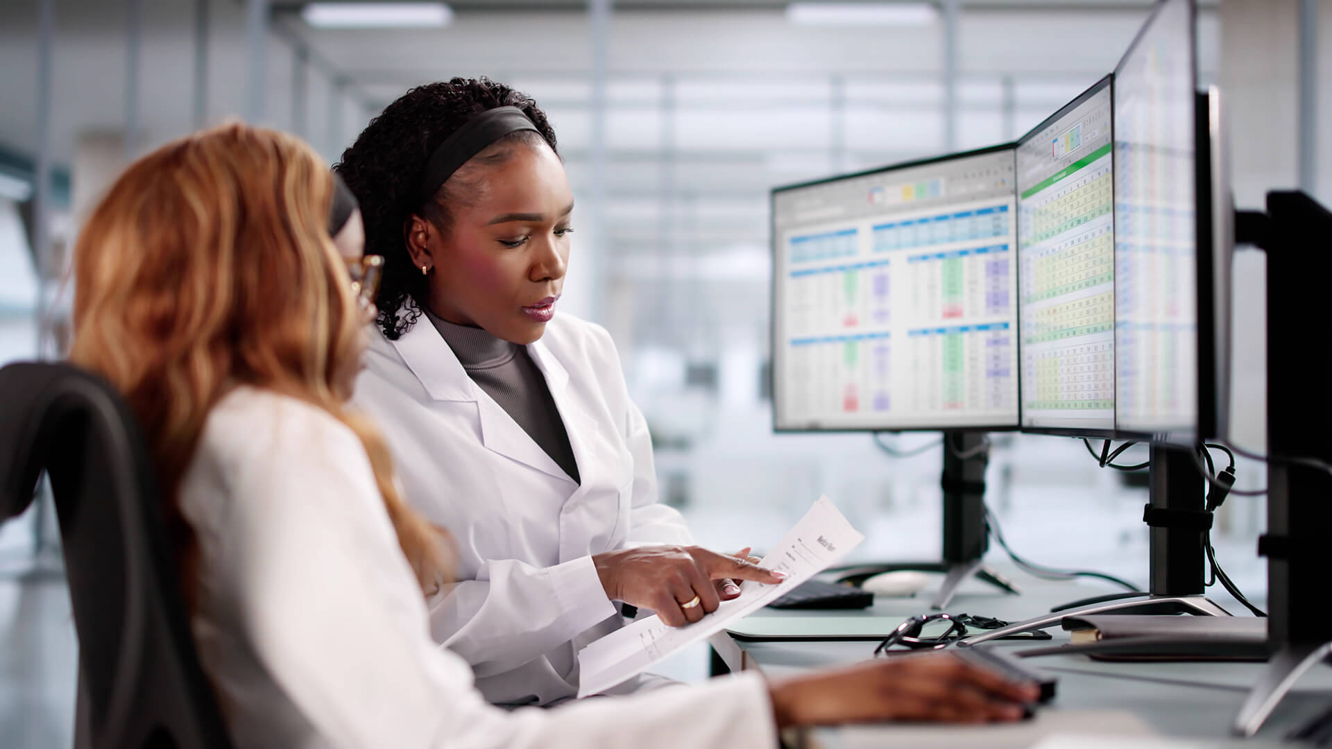 Clinical experts review spreadsheet data together for procurement efforts.