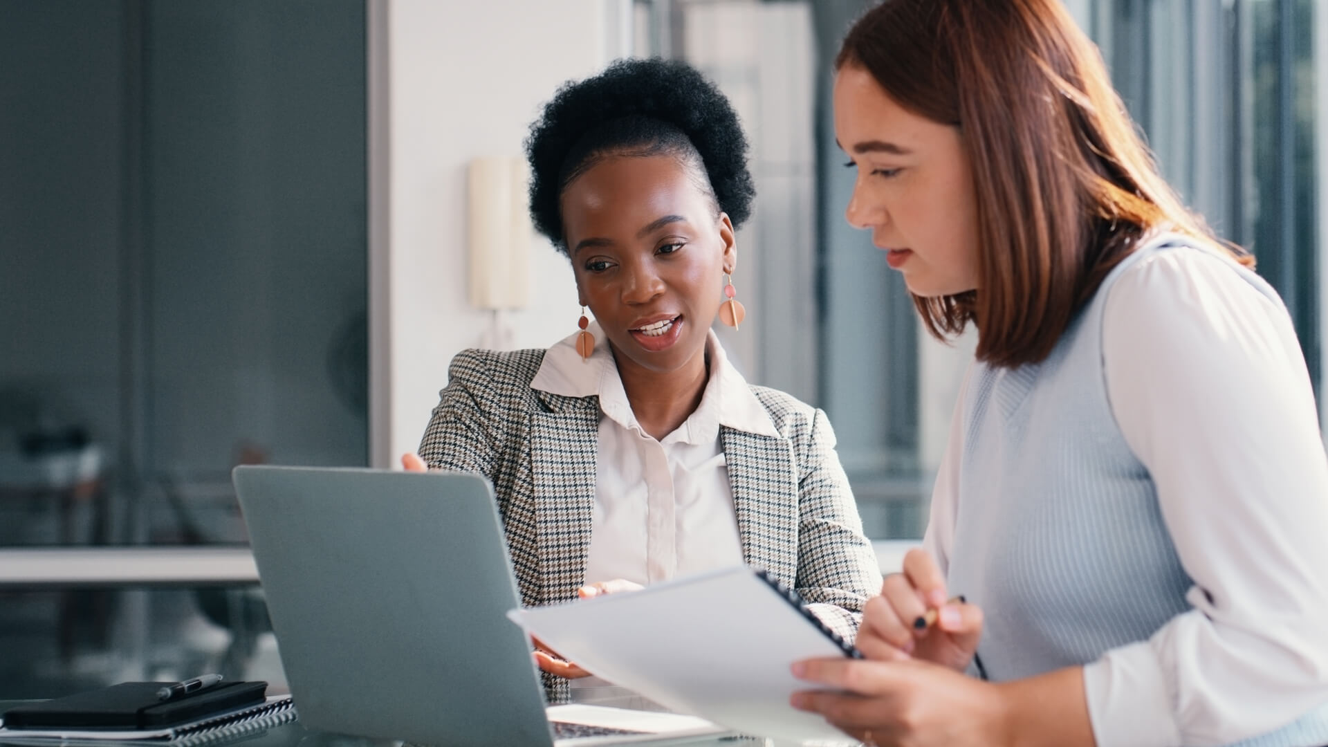 Two female coworkers reviewing the August 2025 jobs report looking at July 2025 labor market and economy trends.