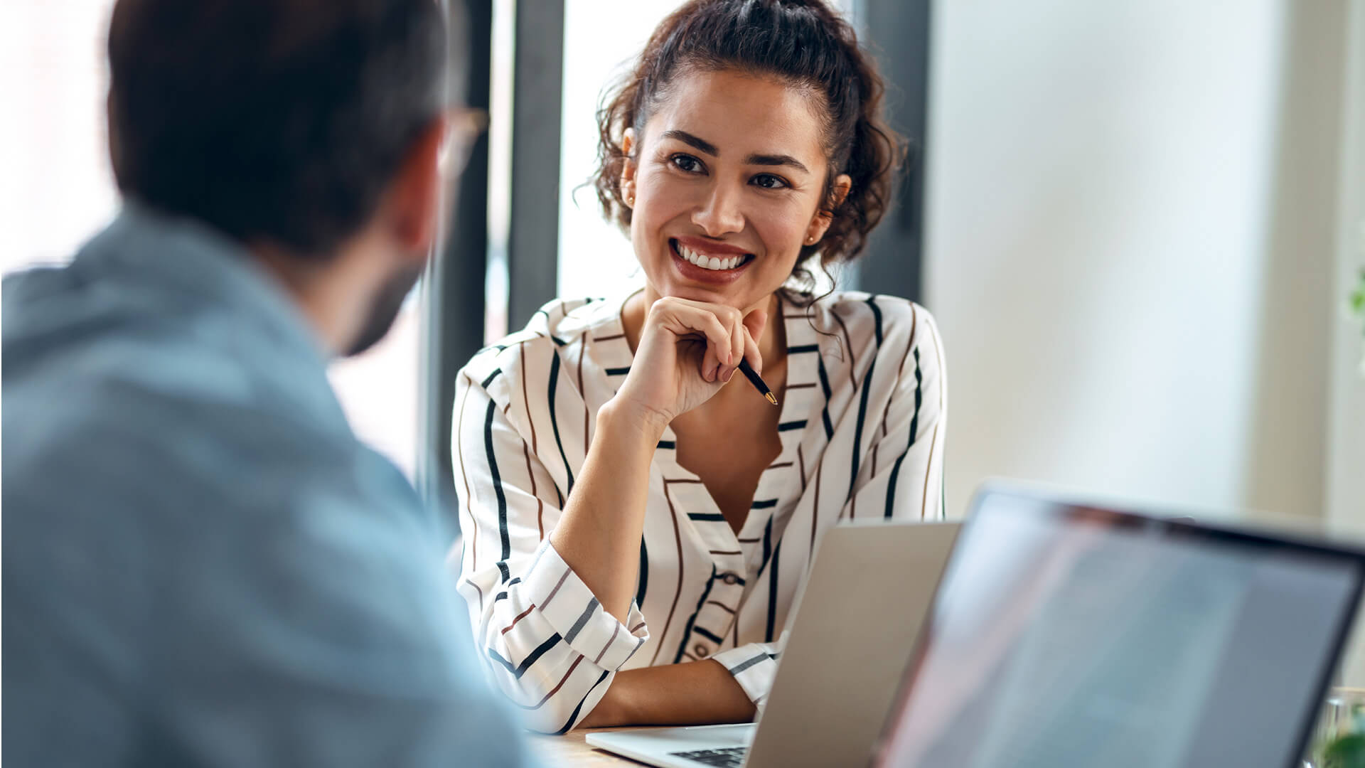 Female and male coworkers discussing and reviewing the June 2025 jobs report on their laptops looking at May labor market and economy trends.