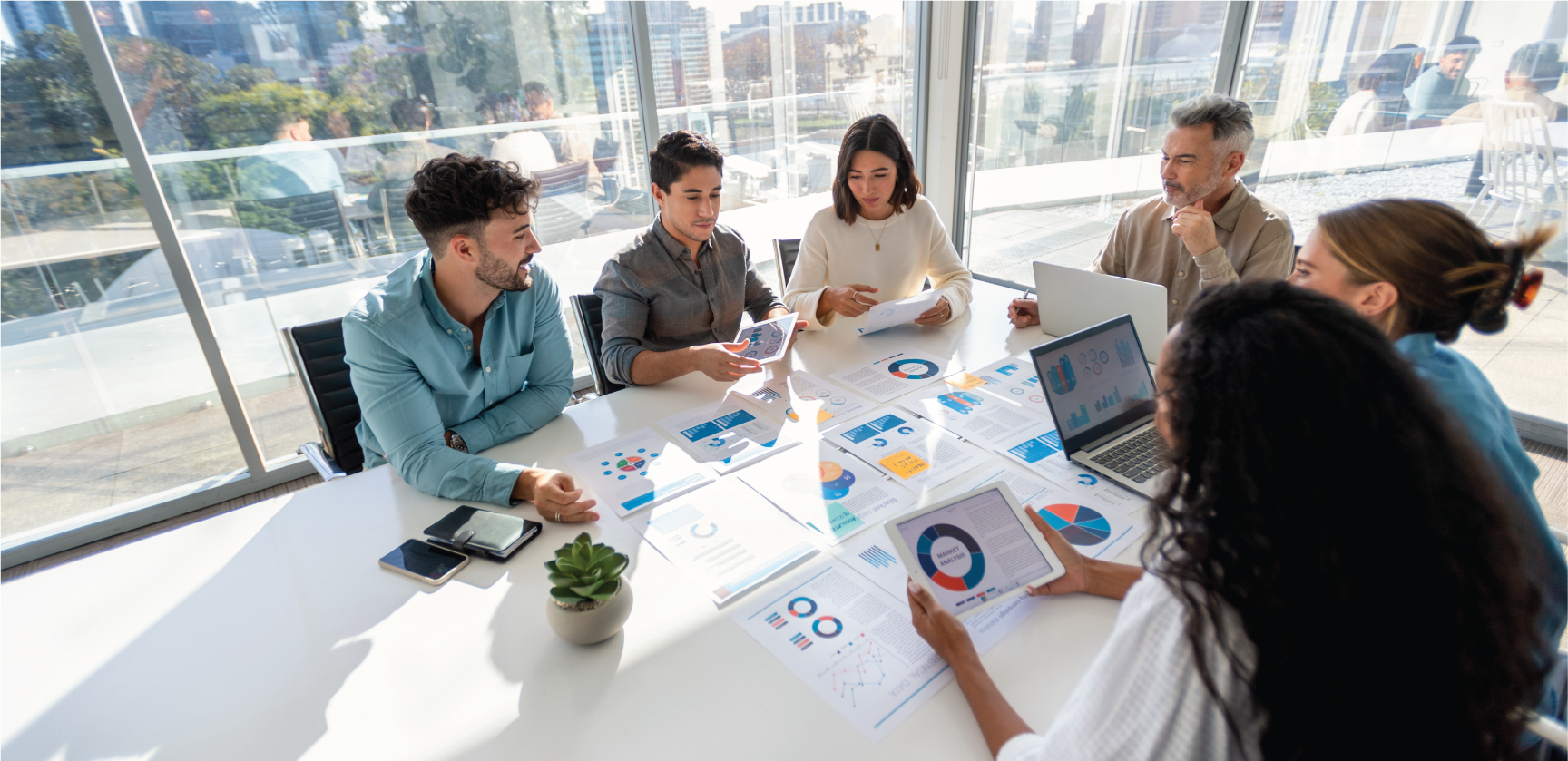 group of people working with paperwork on a board room table