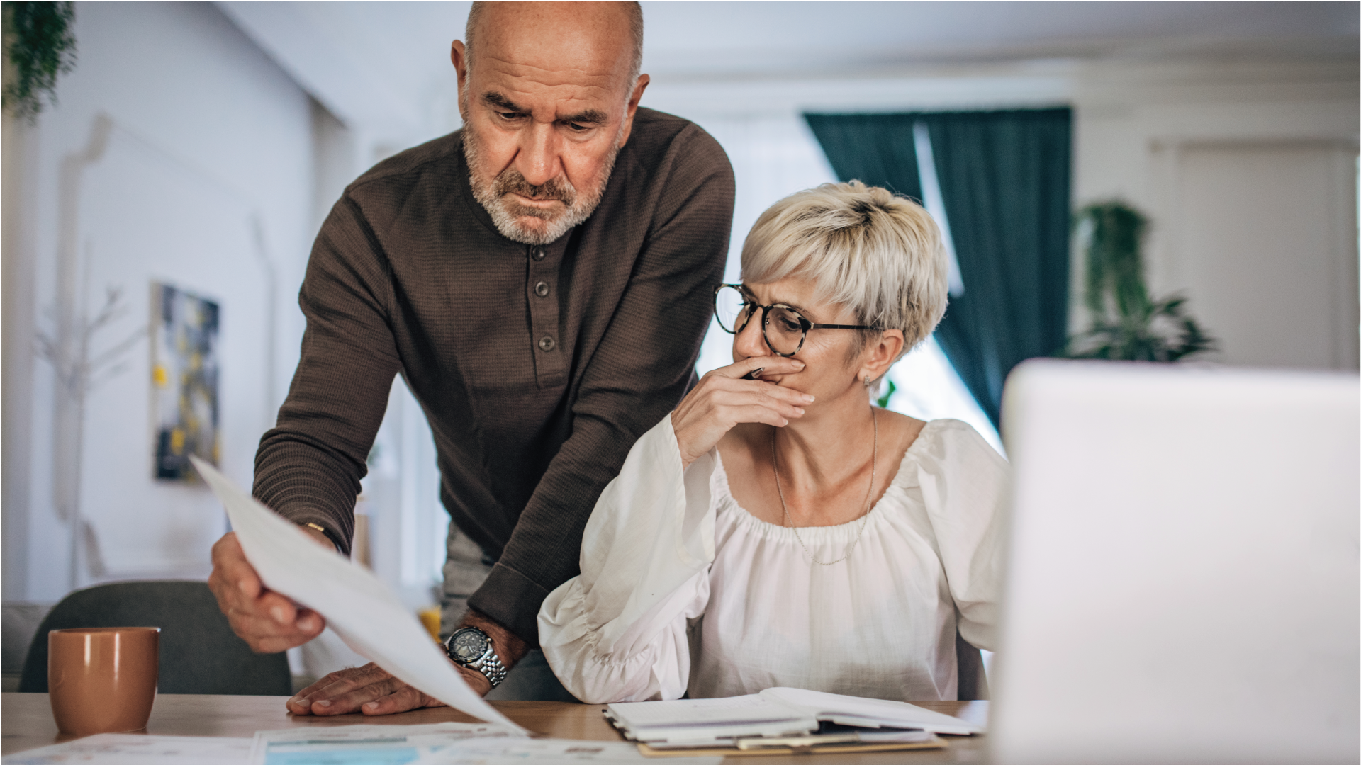 Couple with concerned facial expressions calculating bills at home