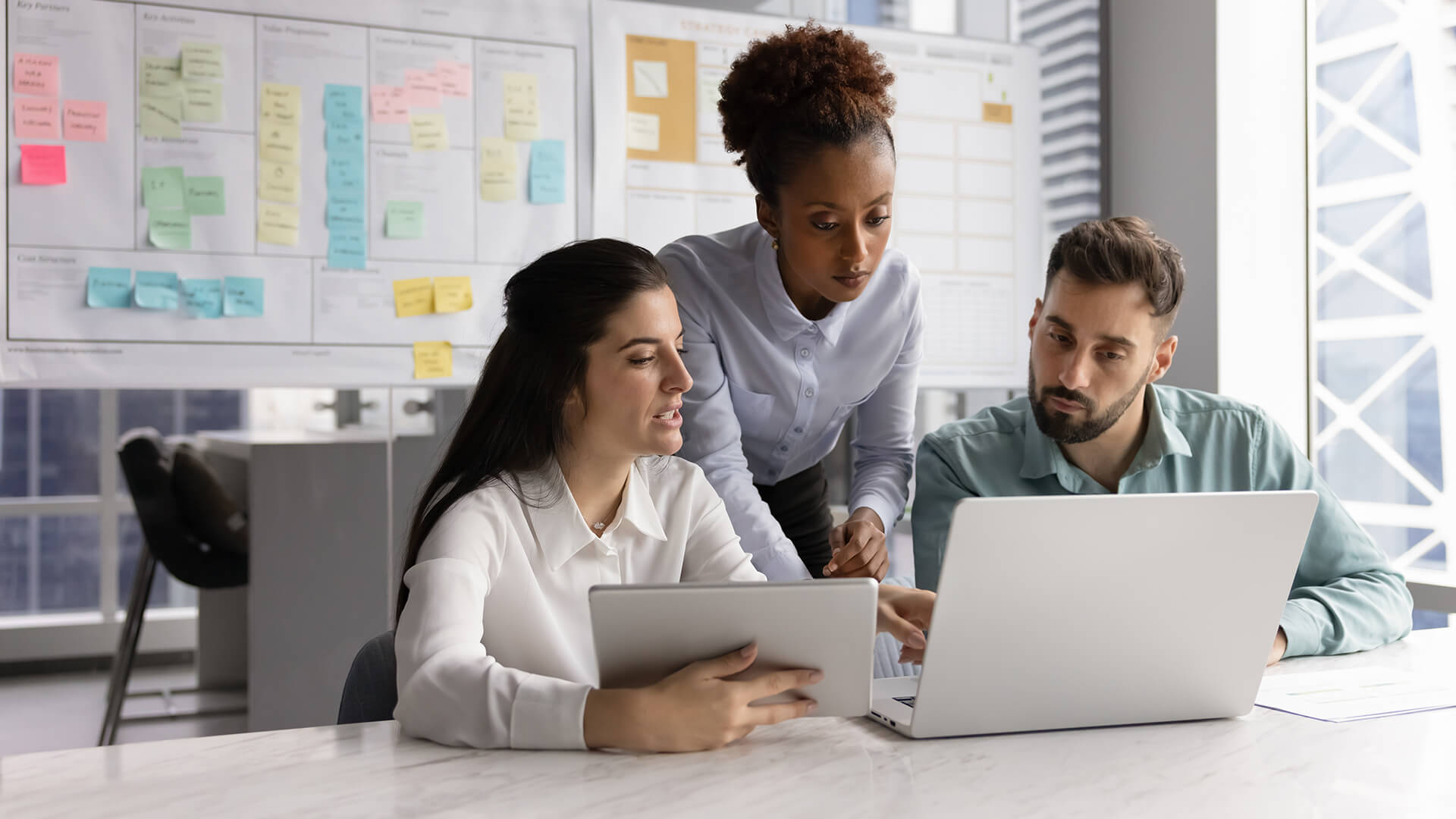 Three coworkers reviewing the Canada labour market and economy report on a laptop looking at Q3 2025 trends.