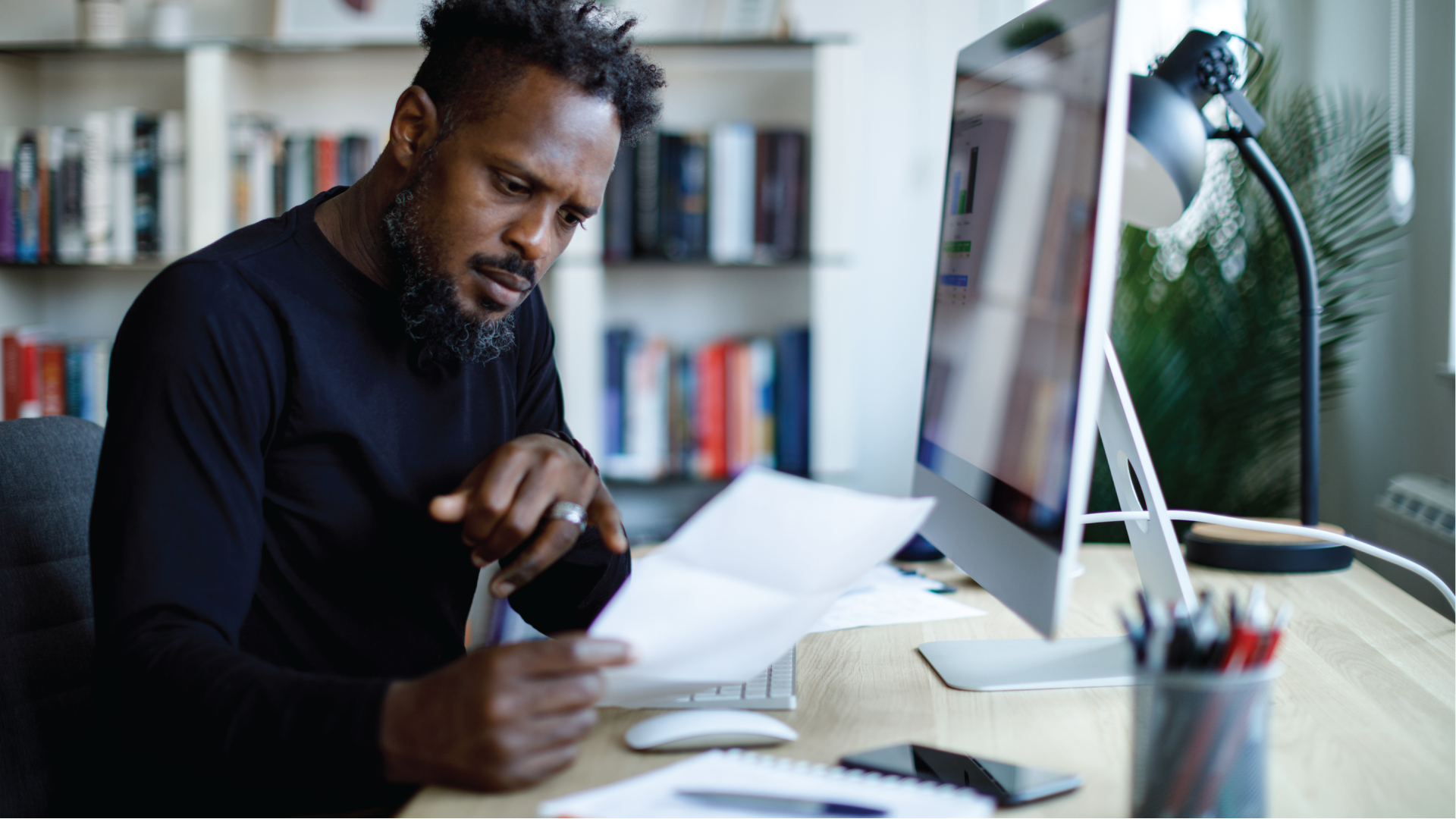 Shocked man sitting at his computer looking at monthly bills