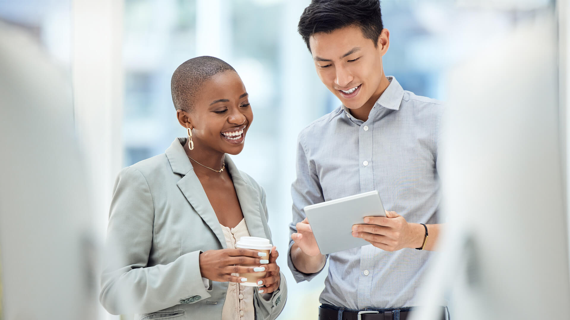 Male and female professionals reviewing the December 2025 jobs report on an iPad looking at November 2025 labor market and ecconomy trends.