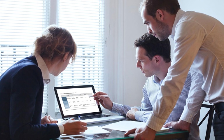 three business workers looking at a chart on a laptop