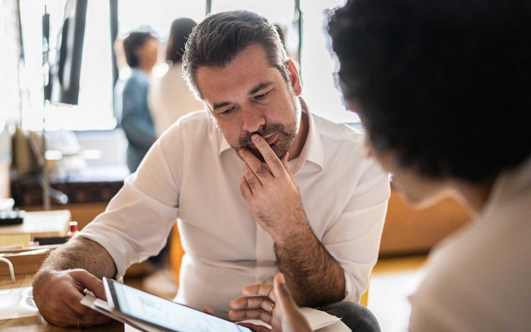 Mature man looking at a digital tablet that a colleague is showing at work